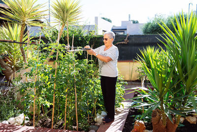 Portrait of young woman standing against plants