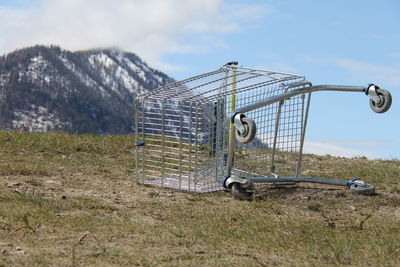 Shopping cart on field against sky