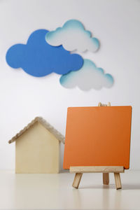 Close-up of model home with clouds and blackboard against white background