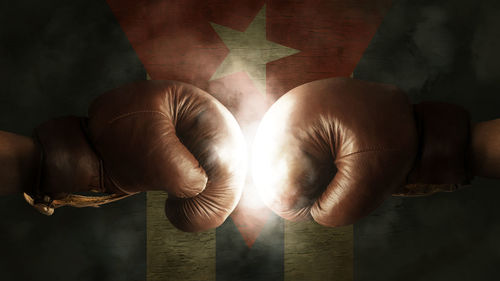 Cropped image of boxers fighting against illuminated cuban flag