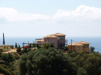 Plants and buildings by sea against sky