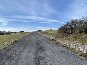 Road amidst field against sky