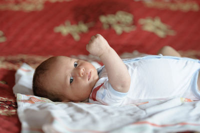 Cute baby girl lying on bed at home