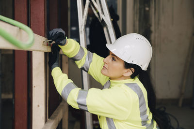 Female engineer marking on wooden plank while working at site