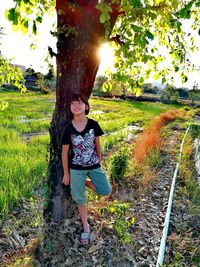 Young woman standing on field against trees