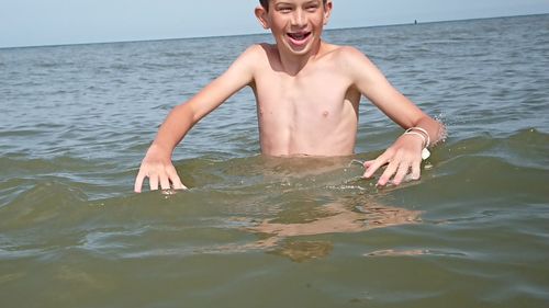 Portrait of shirtless boy in sea against sky