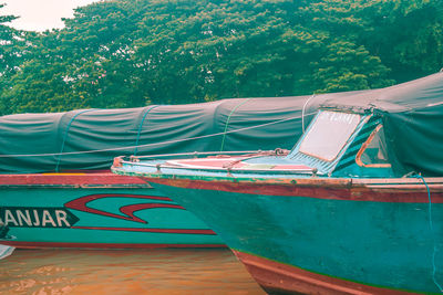 Fishing boat moored on beach against trees