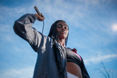 Low angle view of woman looking at camera against sky