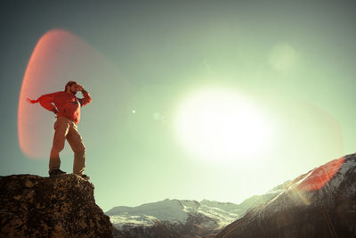 Man standing on rock against sky