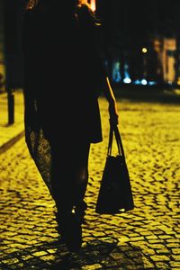 Low section of man standing on street at night