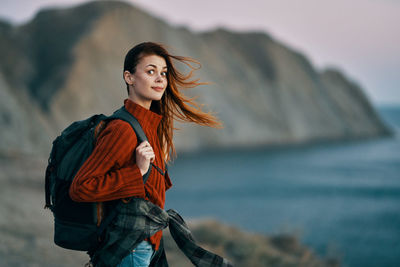 Young woman standing against sea