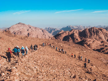 Panoramic view of people in desert against blue sky