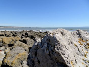 Rocks on beach against clear blue sky