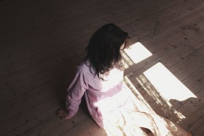 High angle view of young woman sitting on floorboard