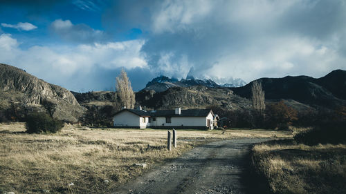 Houses on field by mountain against sky