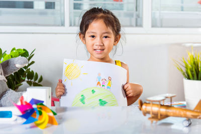 Portrait of smiling young woman using digital tablet on table