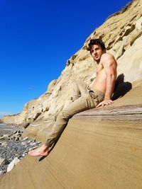 Full length of shirtless young man lying on rock