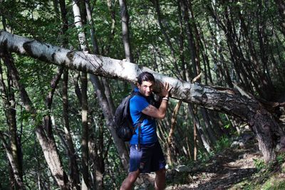 Young man standing on tree trunk in forest