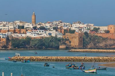 Boats in sea against buildings in city