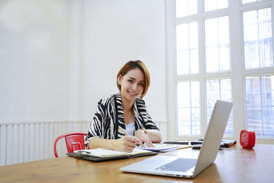 Young woman using phone while sitting on table