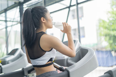 Young woman drinking water from bottle at gym