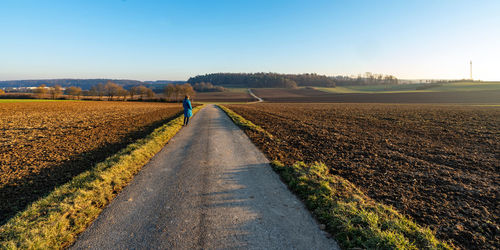 Road amidst field against clear sky