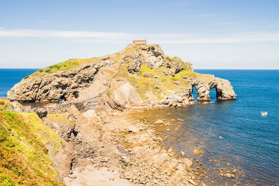 Rock formation on sea shore against sky