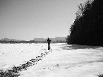 Rear view of man standing on snow covered landscape