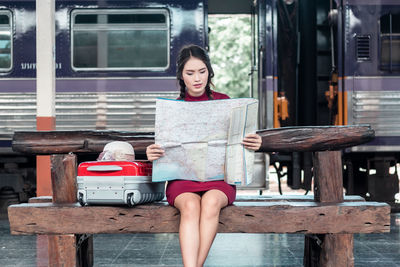 Woman sitting on bench at railroad station