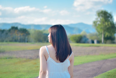 Side view of young woman standing against lake