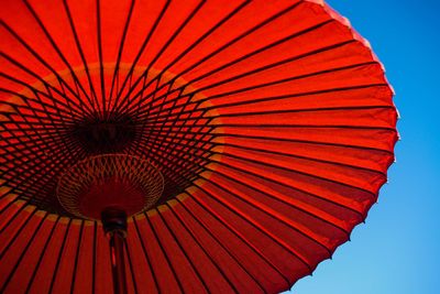 Low angle view of red parasol against clear sky