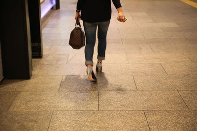 Low section of woman walking on tiled floor