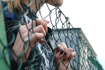 Close-up of woman holding chainlink fence