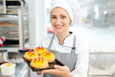 Portrait of young woman holding ice cream in kitchen