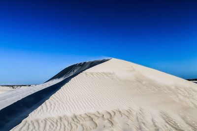 Scenic view of snow covered mountain against clear blue sky