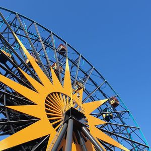 Low angle view of ferris wheel against blue sky