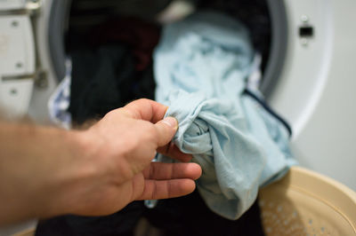 Cropped hand of man washing clothes in machine