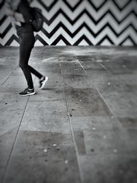 Low section of woman walking on zebra crossing in city