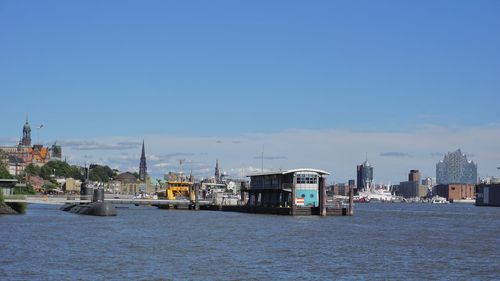 Buildings by sea against clear blue sky