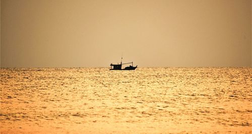 Sailboat sailing on sea against clear sky during sunset