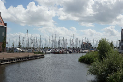 Sailboats moored in calm sea against cloudy sky