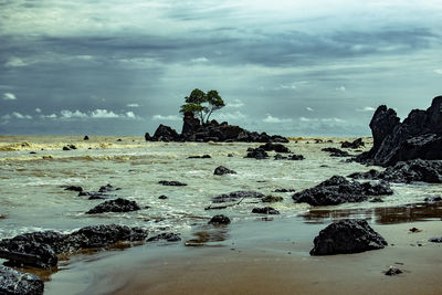 Rock formation on beach against sky