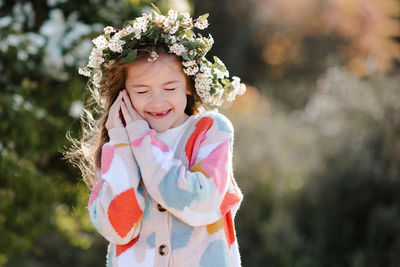 Happy smiling kid girl 6-7 year old wear knit colorful sweater wreath hairstyle with flowers