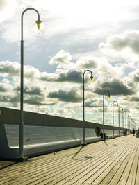 Street light on pier by sea against sky