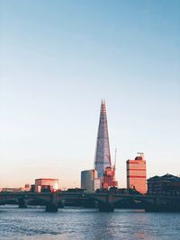View of buildings by river against clear sky