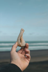 Midsection of person holding stick on beach