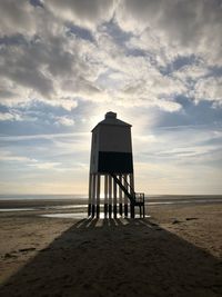 Lifeguard hut at beach against sky during sunset