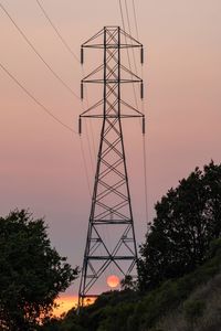 Low angle view of silhouette electricity pylon against sky during sunset