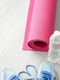 High angle view of pink exercise mat with water bottle on hardwood floor
