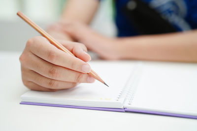 Midsection of woman writing in book